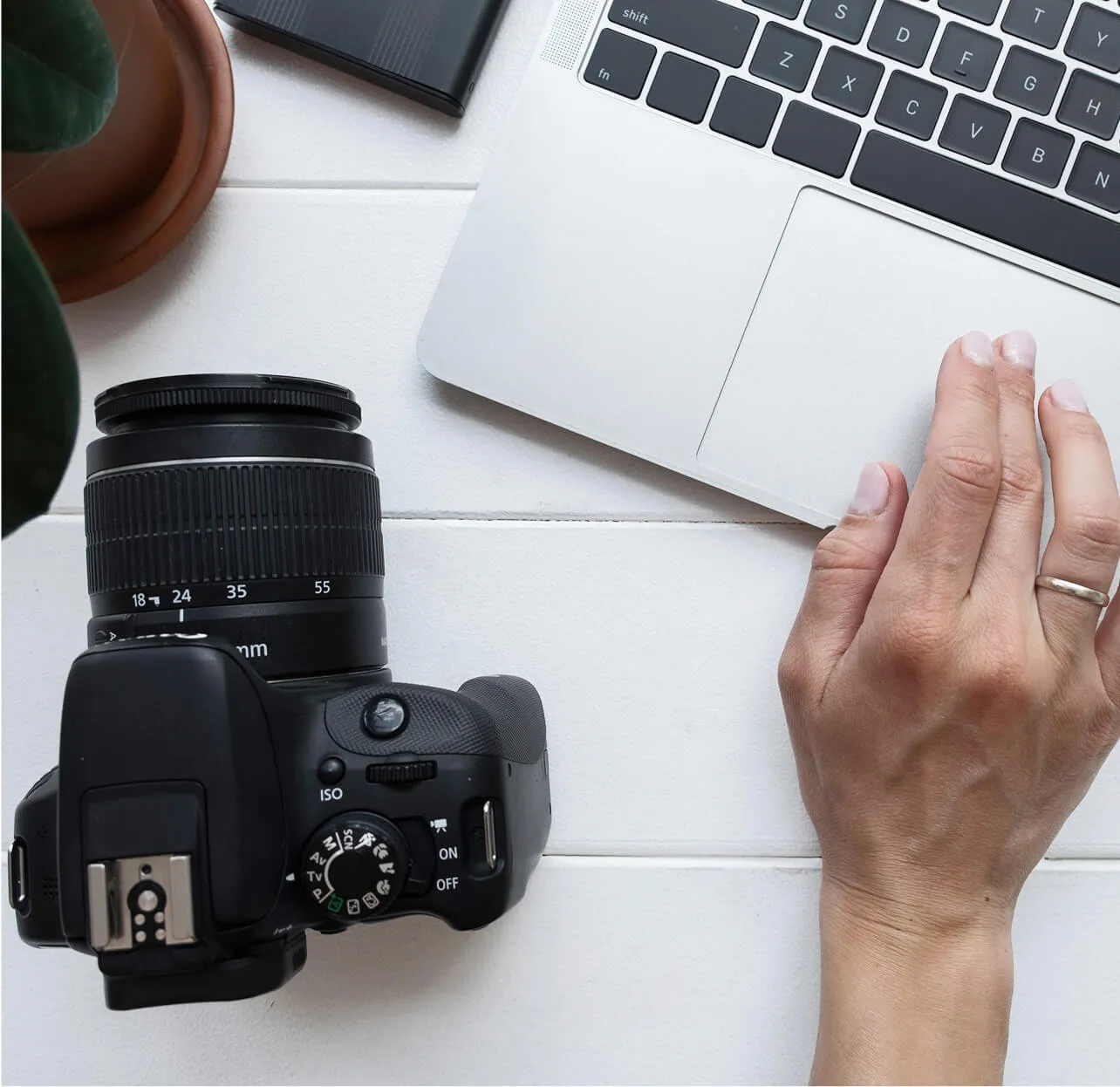 Desk view with camera, notebook and right hand