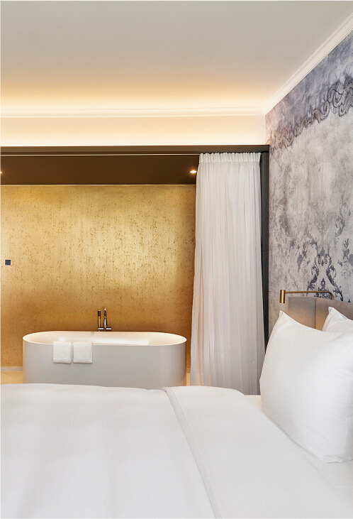 Blick auf ein sonniges Bett und Hotelzimmerinterieur mit Blick aus einem großen Fenster